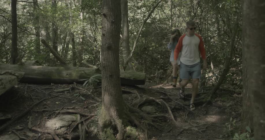 A man and woman hike through a forest trail