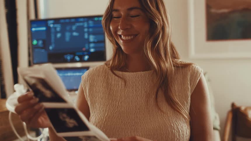 Happy pregnant woman holding baby ultrasound scans in a clinic