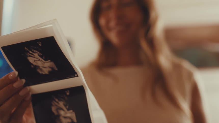 Expectant mother smiles while looking at ultrasound pictures