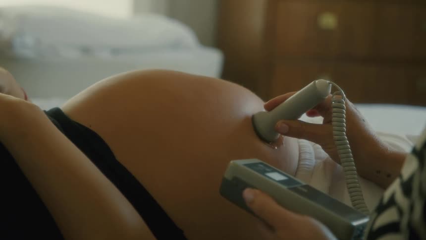Technician performing an ultra sound on a pregnant womans belly