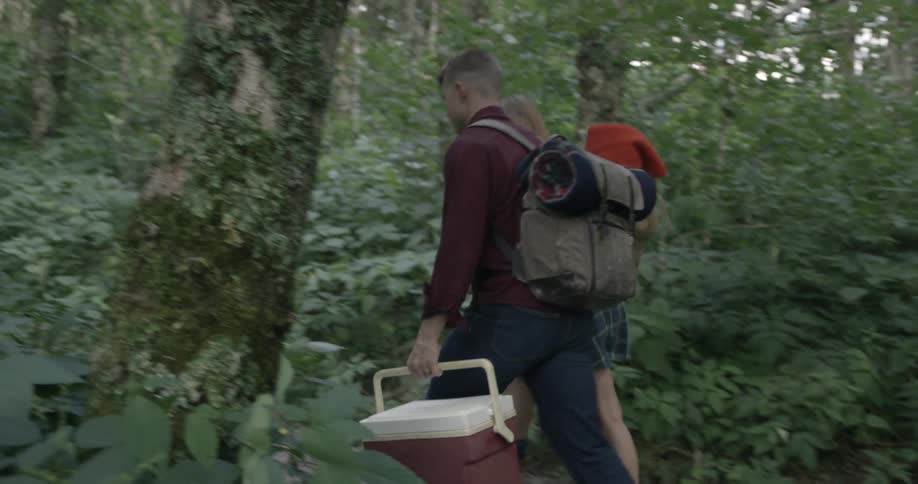 People walk uphill carrying camping equipment