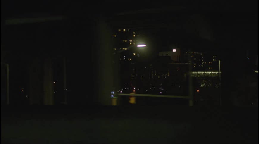 The camera is in a moving car looking out the window at a highway at night blurry lights from streetlights and other vehicles streak by