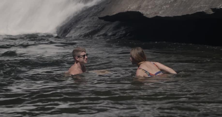A man and woman swim in a river