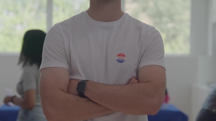 The man has a sticker on his shirt that says i voted