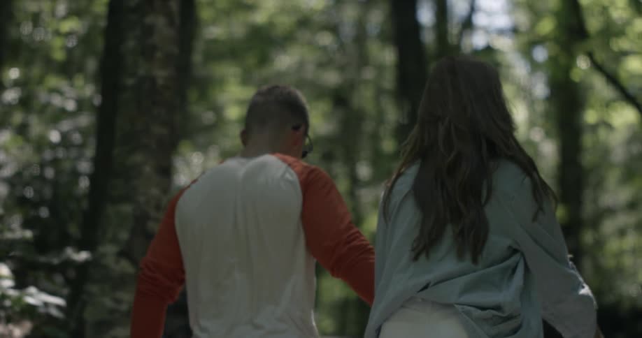 A man and woman hold hands walking up a trail