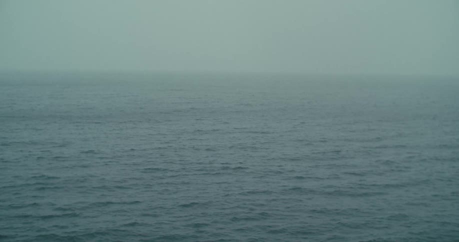 A vast gray ocean with small waves on the surface with the horizon line blurred into a hazy sky