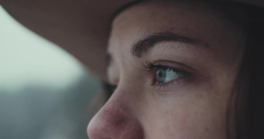 A closeup of a woman gazing thoughtfully ahead outdoors