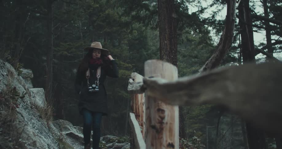 A woman walks along a path in the woods towards the camera