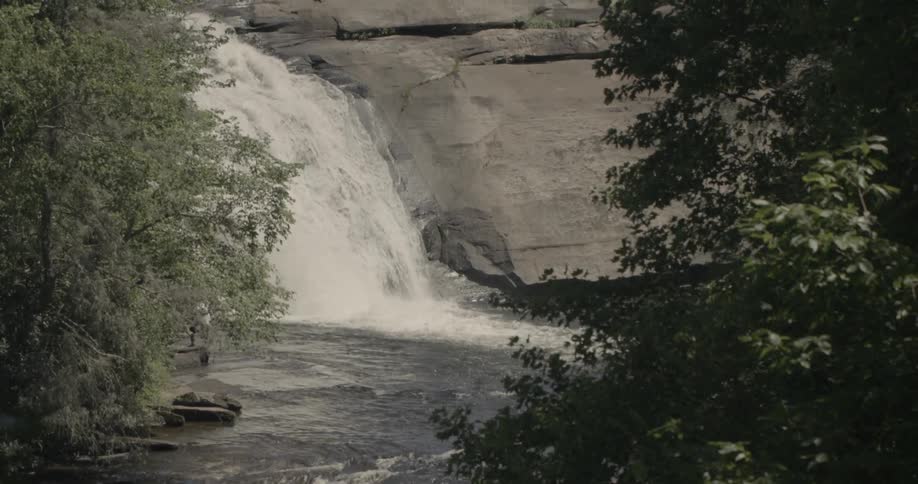 The waterfall is spraying into the stream below
