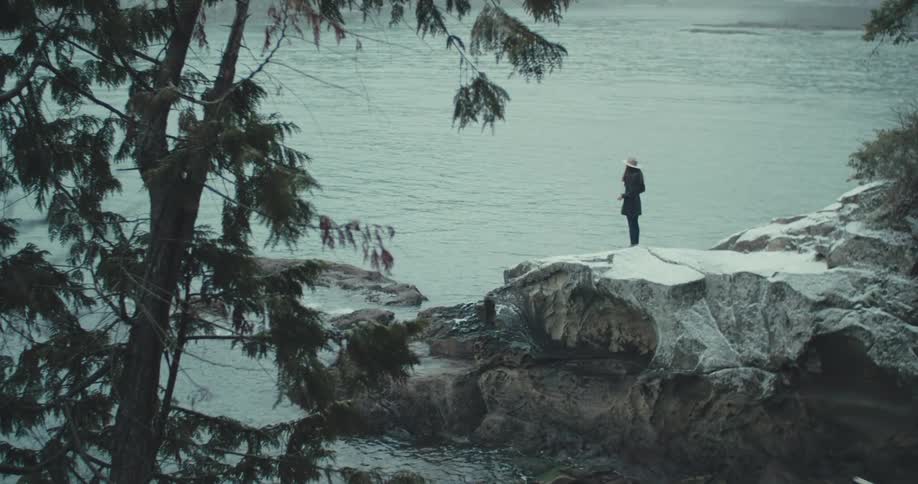 A woman takes photos on rocky cliffs by the water
