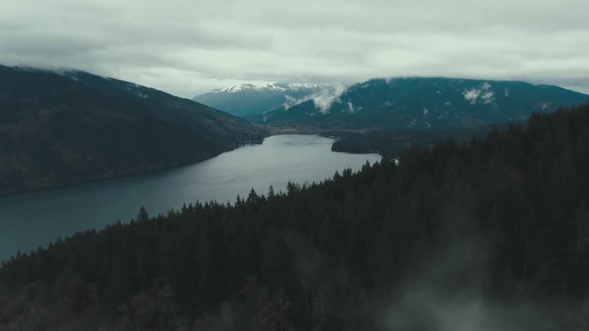 Deep valley with a winding lake is surrounded by forestcovered mountains