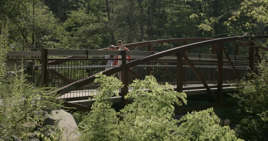 A man and woman walk across a bridge