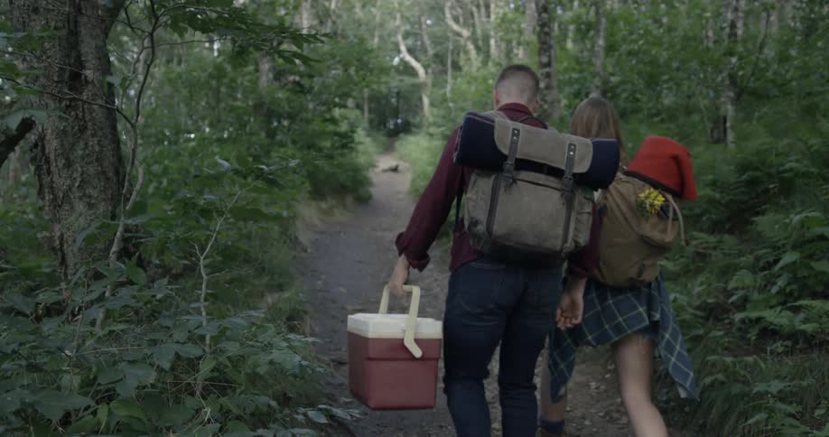 A man and woman hike through a forest trail