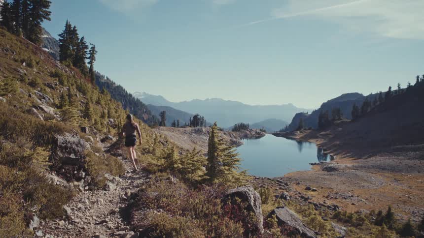 Woman running on a mountain trail by a lake