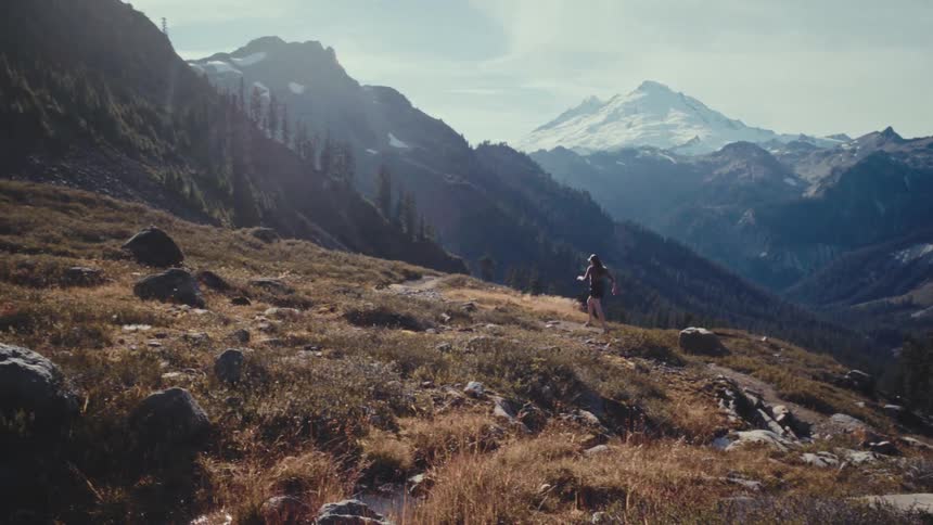 Woman runs along a path in the mountains on a cloudy day