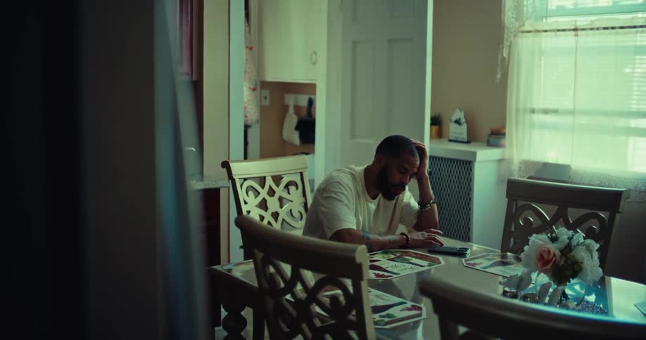 The man is sitting at home tapping on his cell phone