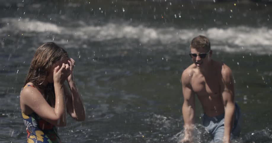 Couple playfully splashing each other in a beach scene