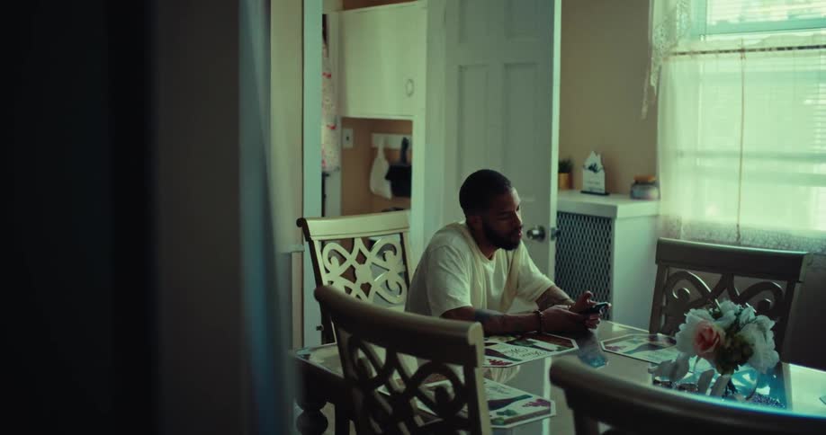 A person sits at a dining room table and uses a phone