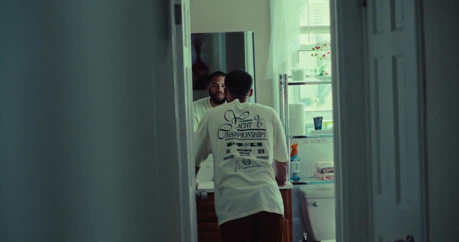 The man is looking in the bathroom mirror