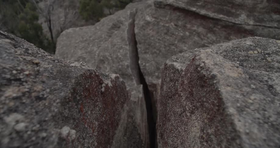 A deep crack runs through the surface of large rocks on a mountain