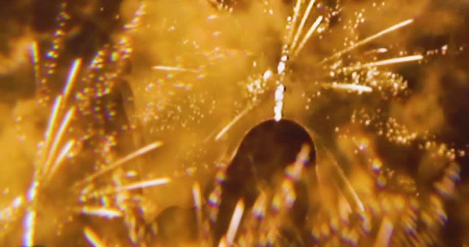 A dramatic closeup shows a large cluster of vibrant blurred fireworks exploding in the night sky the sparks and bright streaks of light fill the frame creating an abstract dynamic display
