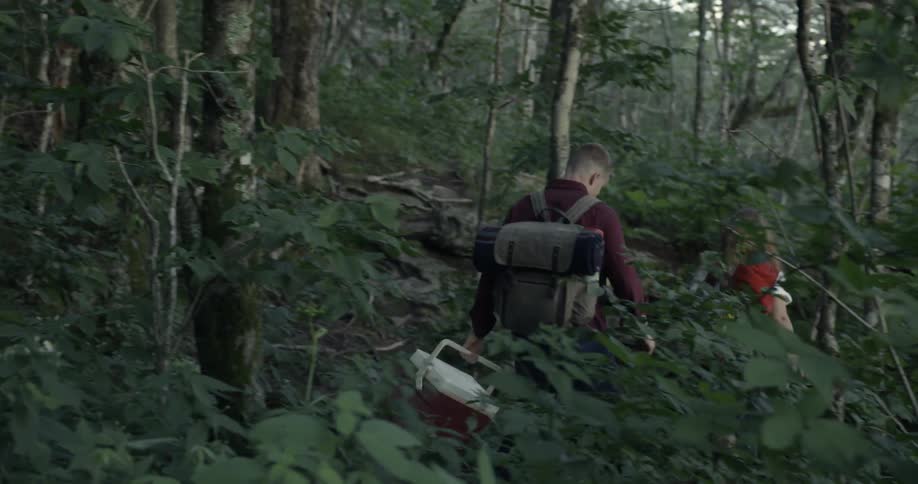 People hike downhill in dense woods