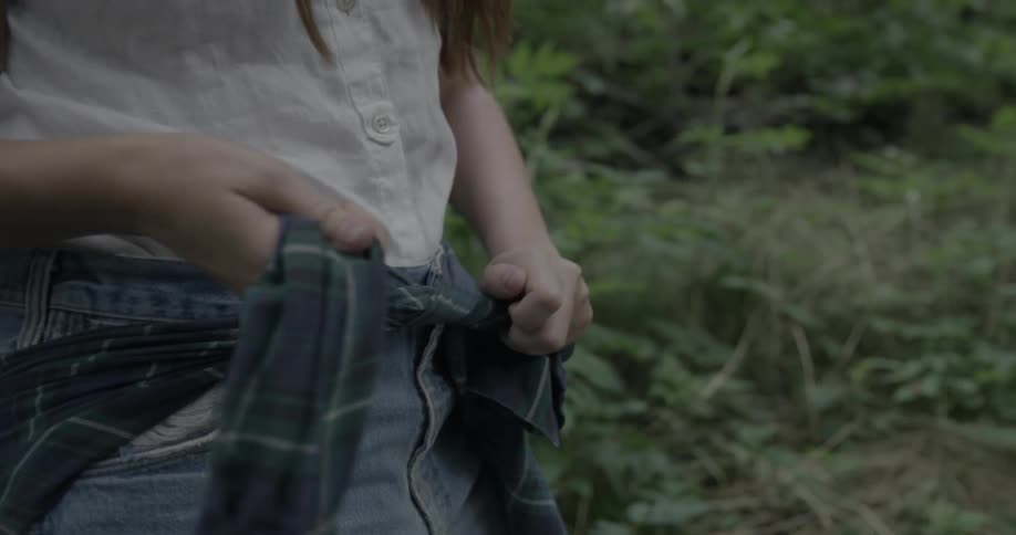 A woman ties a shirt around her waist