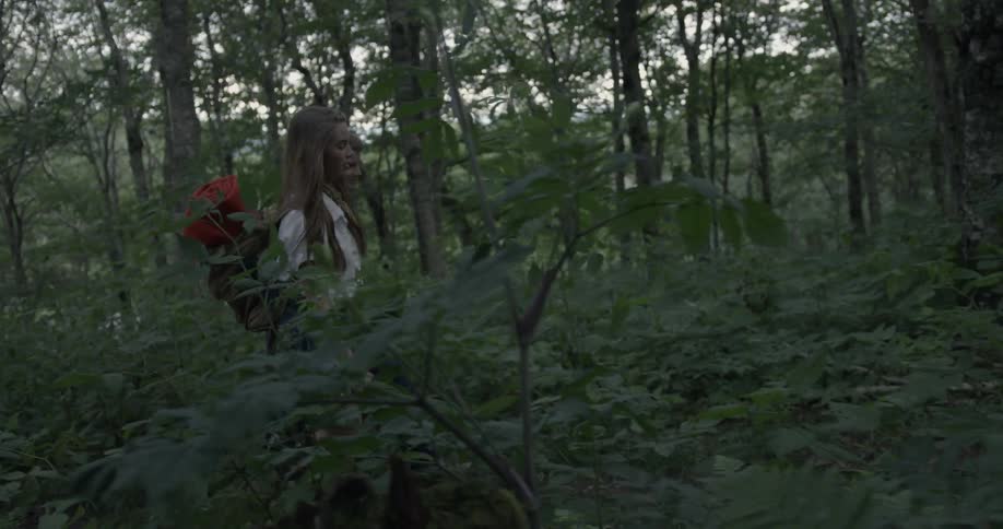 A man and woman hike through a forest