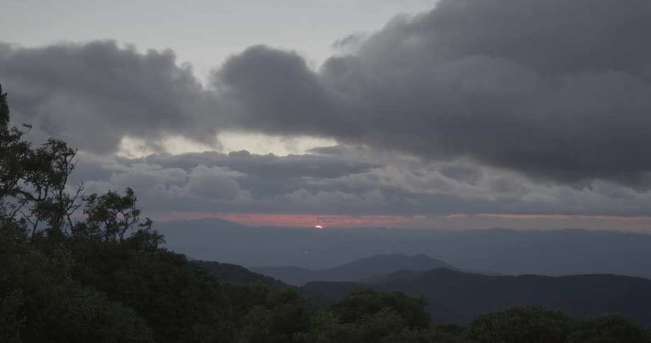 The sun is setting behind the clouds in the distance