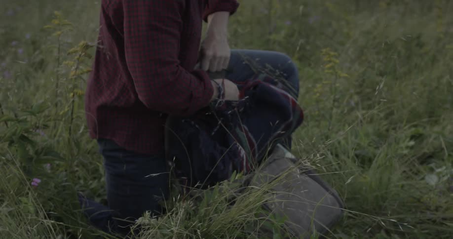 A man is putting items in his backpack