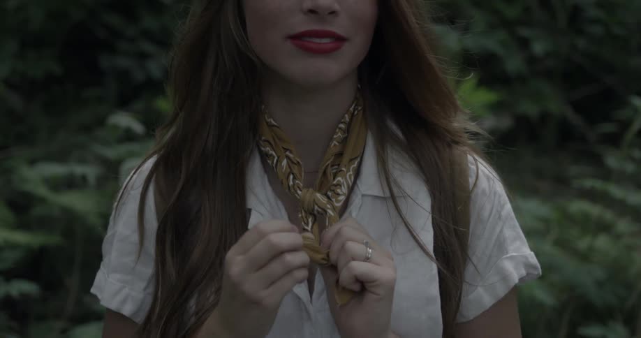 A woman ties the scarf around her neck