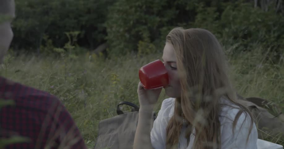 A woman takes a drink from a cup at a picnic