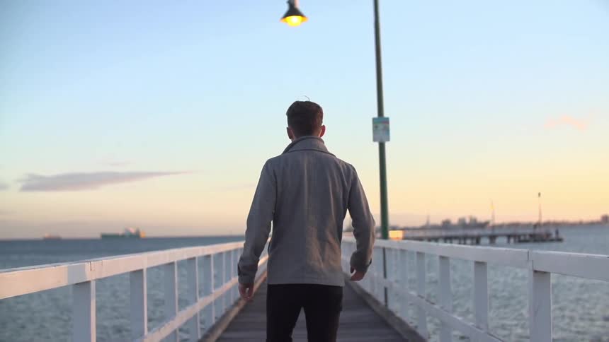 Man walking on an ocean pier at sunset