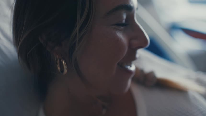 A woman lying down smiles warmly her face lit with joy and relief