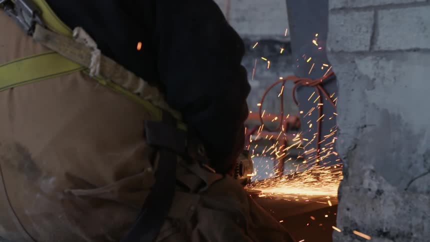 A person cutting metal, and spark are flying everywhere