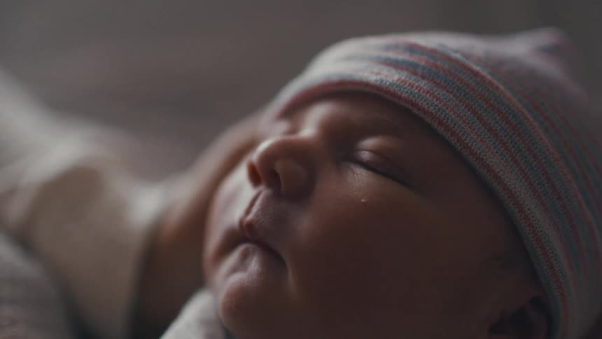 Newborn infant falls asleep in the arms of their mother