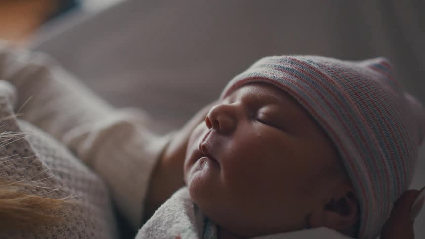 Portrait of a newborn baby sleeping in a persons hands