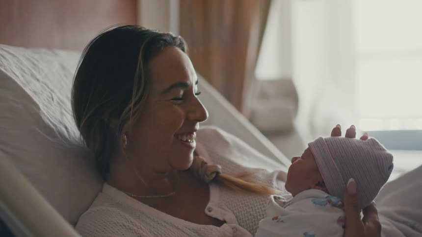 Smiling mother with newborn baby on her lap