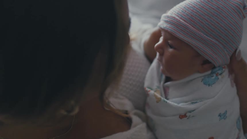 Mother holding newborn baby in her lap