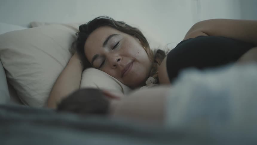 A woman and her newborn baby sleeping on a bed