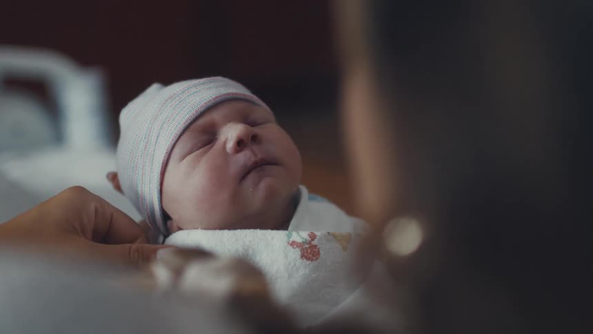Person caressing the face of a sleeping baby