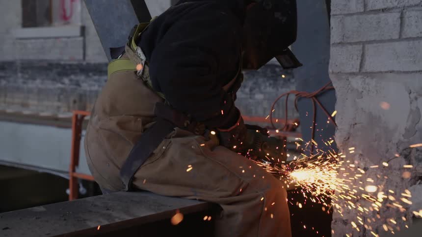 A construction worker uses a grinder