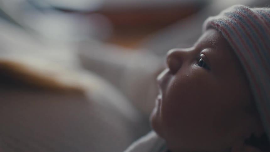 Mother holds her newborn while lying in the hospital