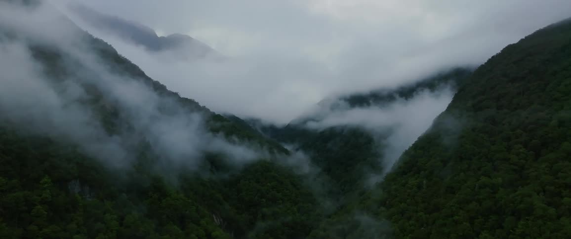Aerial view of mountain valley where clouds are passing by making it eye catching view