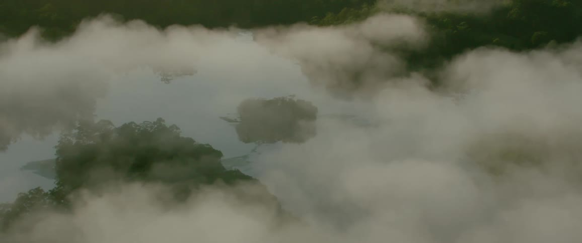 A camera moves down through clouds to reveal mountain tops