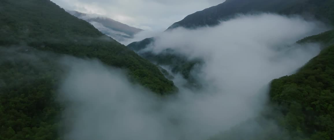 A view of mountains shows clouds rising from the bottom of a valley
