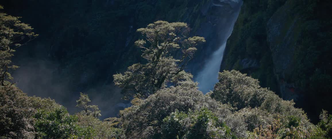 The waterfall rages off the cliff of the mountain