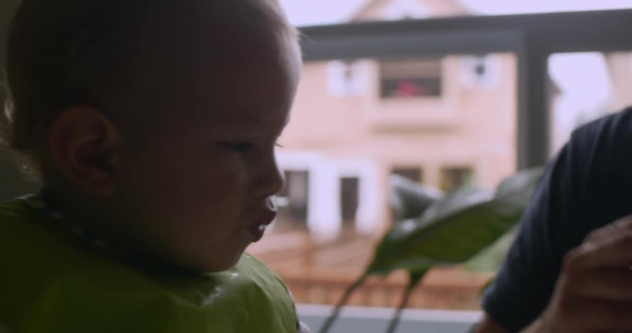 Infant being spoon fed by his father