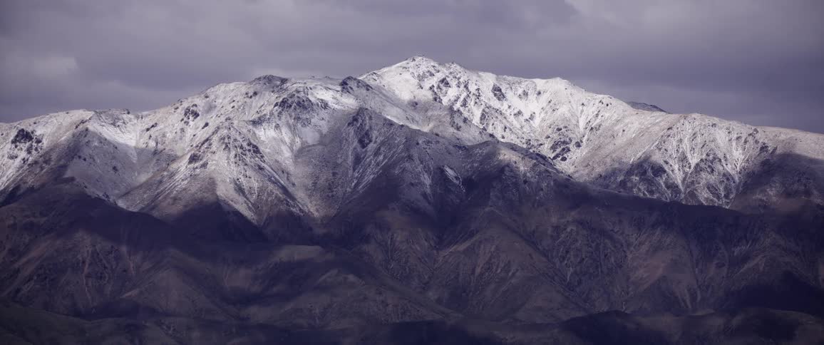 Timelapse of snowy mountain peaks under shifting clouds and light