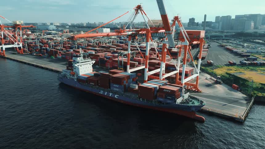 A cargo ship is docked at a busy port terminal on the ocean